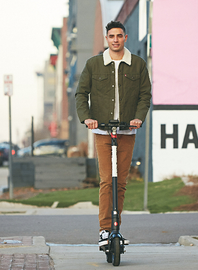 Smiling guy on an electric scooter in town